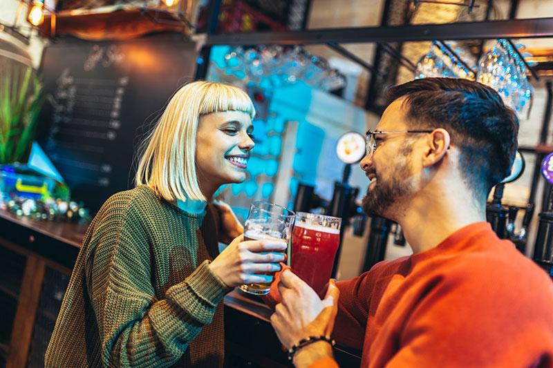 Junges Paar an einer Bar mit Bier in der Hand