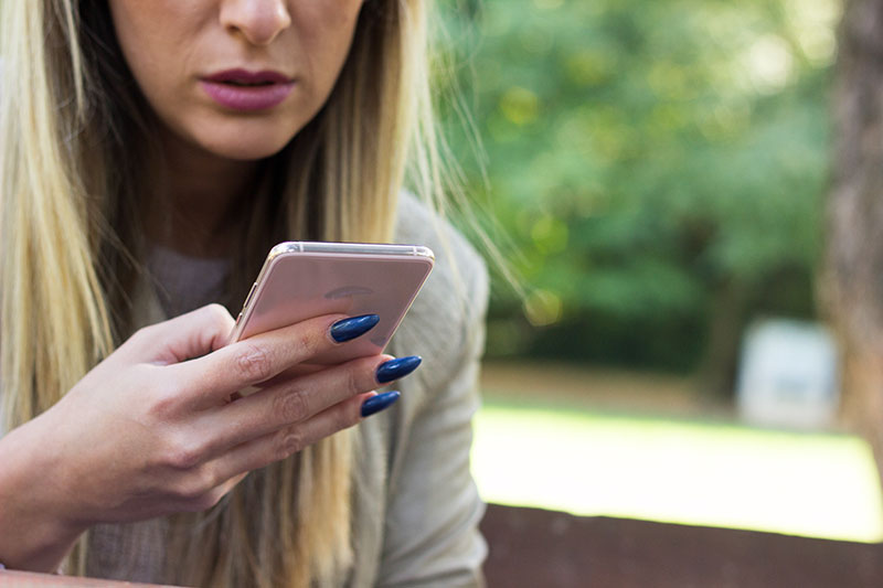 Nahaufnahme von blonder Frau mit Smartphone in der Hand