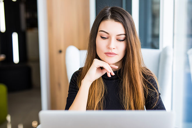 Junge Frau schaut nachdenklich in ihrem Computer